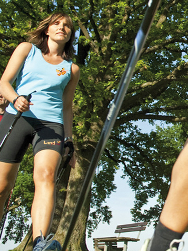 Nordic Running Sportler in dynamischer Laufbewegung mit aktiver Stocktechnik; moderne Trainingsform zur Steigerung von VO₂max, Fettverbrennung und Herz‑Kreislauf‑Fitness für ein langes, gesundes Leben.
